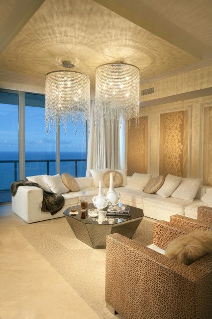 A living room with a shimmering chandelier and a view of the ocean.