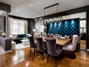 A dining room with hardwood floors, a blue upholstered wall, and velvet accents.