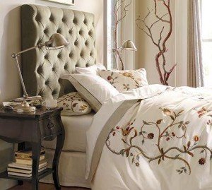 A velvet bed with an upholstered headboard and pillows.