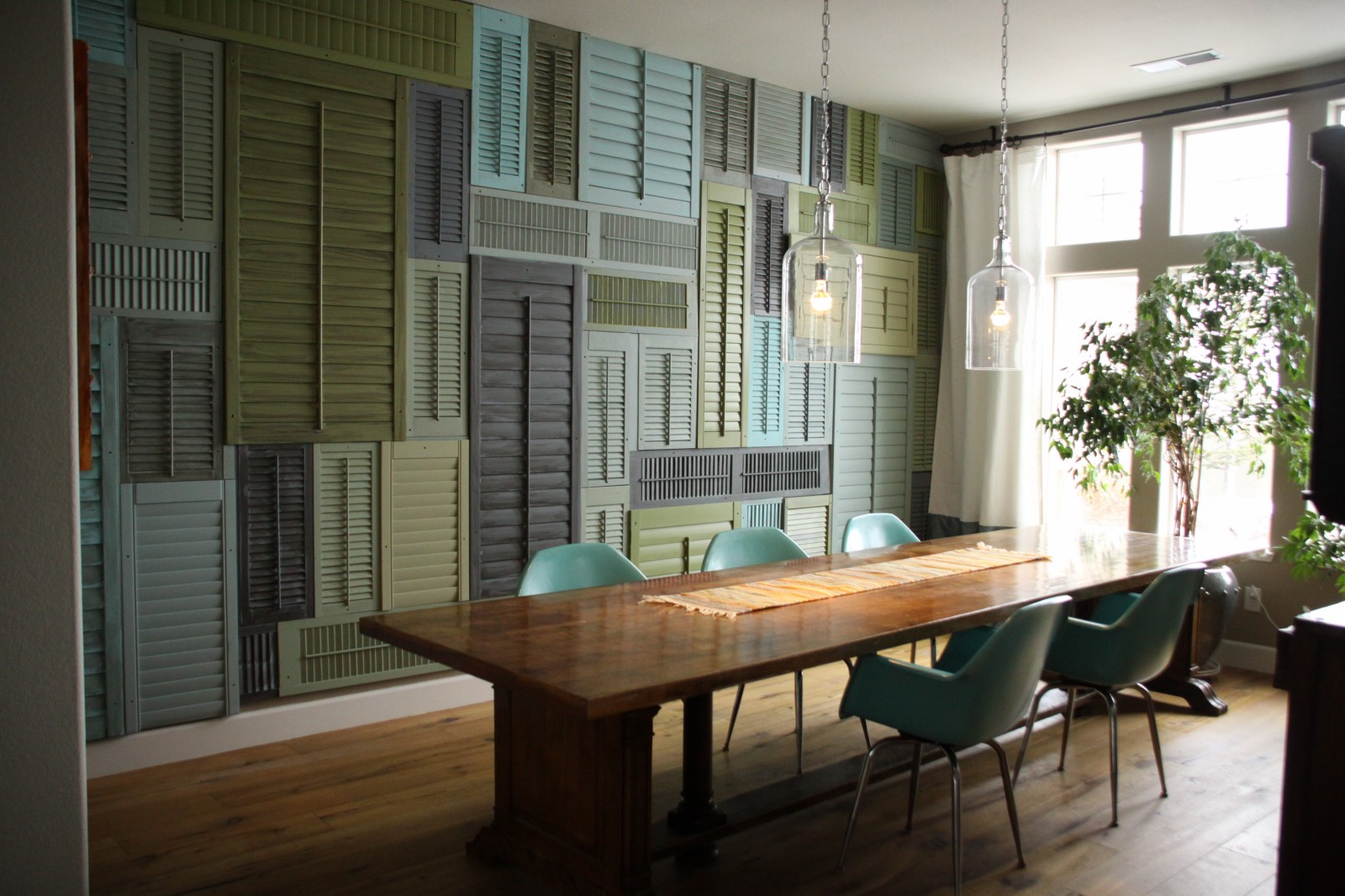 A dining room with repurposed old window shutters on the wall.