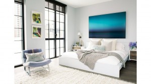 A white bedroom with a large painting on the wall, incorporating one of the top bedroom colors of 2015.