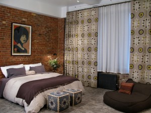 A bed in a room with a brick wall featuring top bedroom colors of 2015.