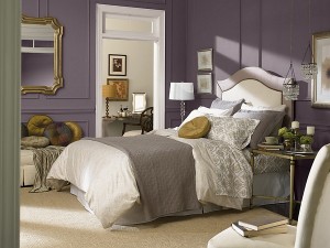 A bedroom with trendy purple walls and a cozy bed.