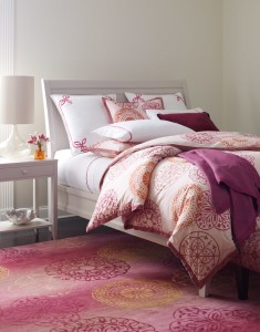 A bed with a pink and orange comforter, popular bedroom colors of 2015.