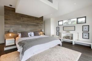 A modern bedroom with wood paneling and a white bed featuring top bedroom colors of 2015.