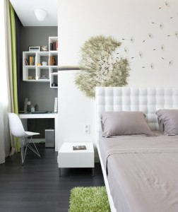 A white bed with a splash of green from a rug.