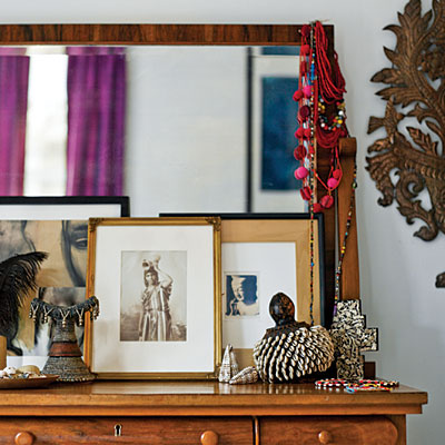 A global chic mirror on top of a dresser.