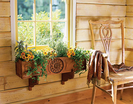 A chair surrounded by flower arrangements in a wooden window box.