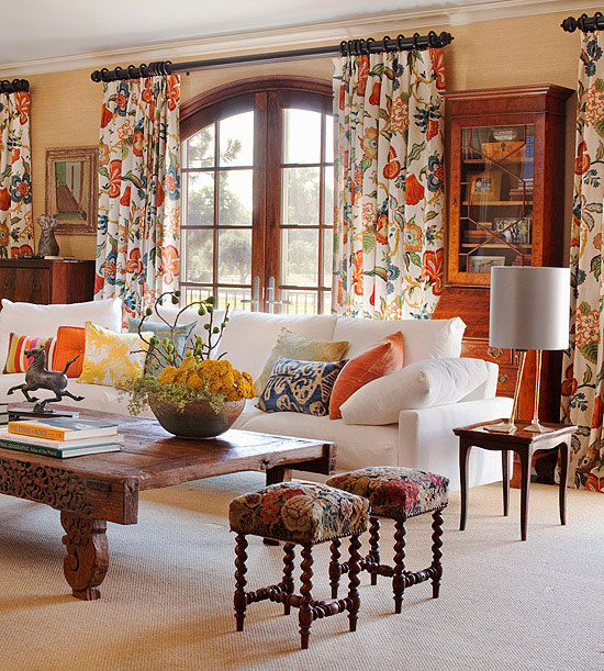 A living room with floral curtains and a table adorned with florals.