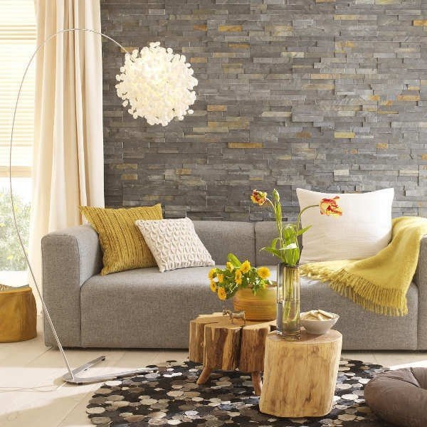 A living room with a grey couch and yellow accents featuring texture.