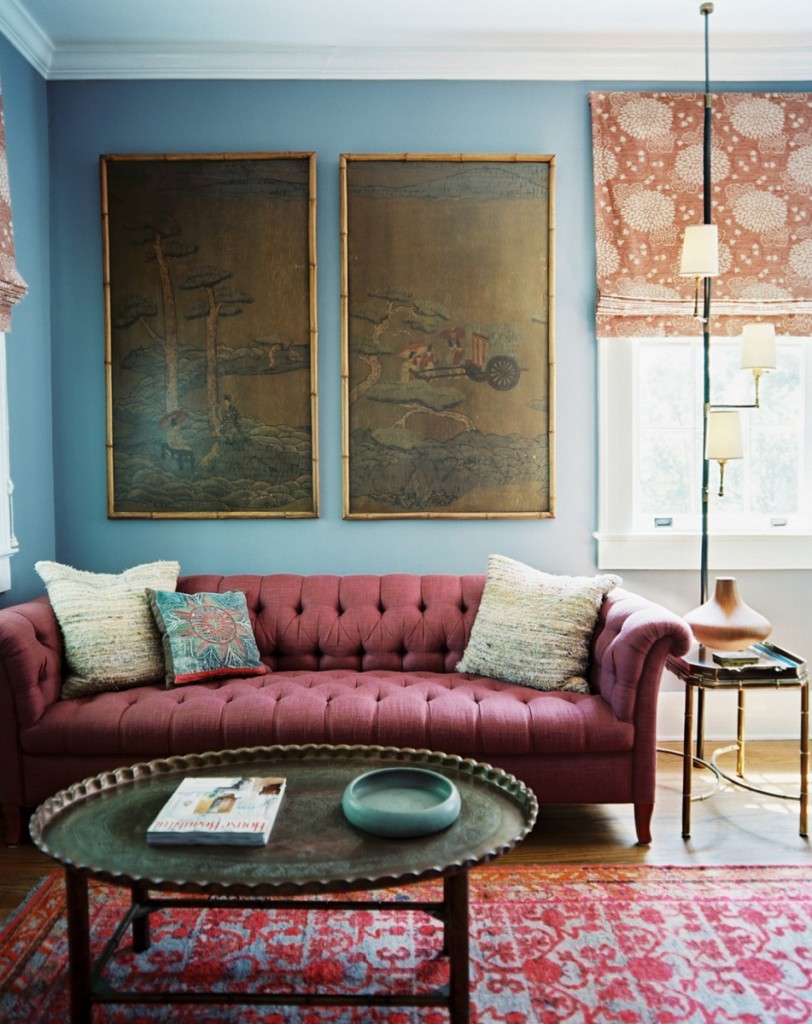 A living room with blue walls and a red couch featuring interior design trends for 2015.