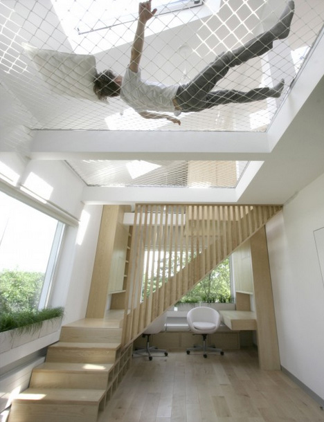 A man is hanging from a hammock in a room.