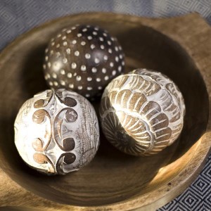 Three wooden balls in a wooden bowl showcase texture.