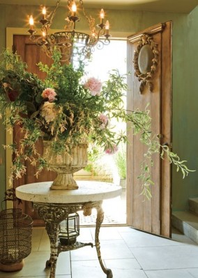 An entryway with a large vase of flower arrangements.