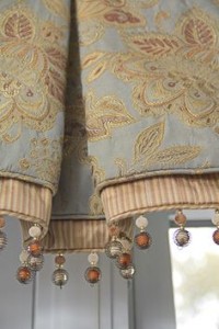 A pair of textured roman shades with beads.
