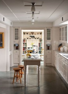 A white kitchen with concrete flooring and a table and chairs.