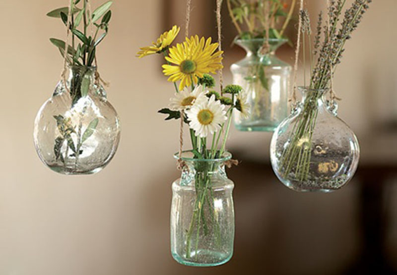 Five hanging vases with flowers in glass jars.