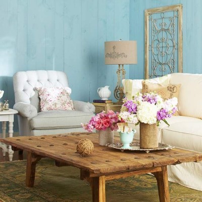 A living room with blue walls and white furniture adorned with beautiful flower arrangements.