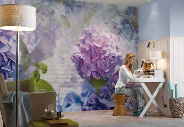 A woman sits at her desk in front of a purple flower mural wallpaper.