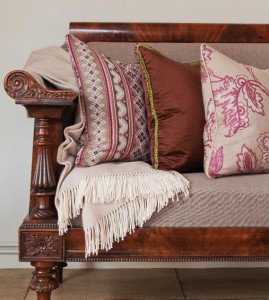 A sofa with pillows and a marsala-colored blanket on it.