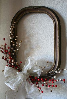 A decorative picture frame with a bow and berries hanging on the wall.