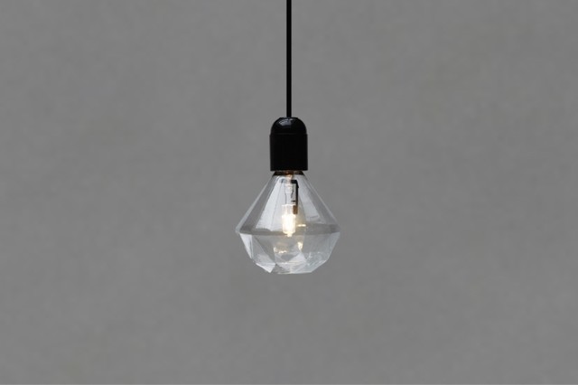 A clear glass pendant light hanging from a black cord, providing an eccentric way to light your bathroom.