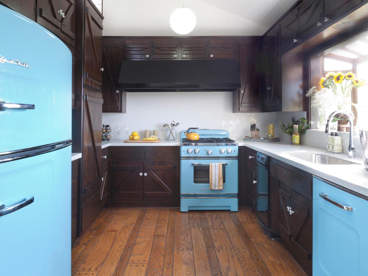 A kitchen with blue appliances and wood floors featuring kitchen cabinets.