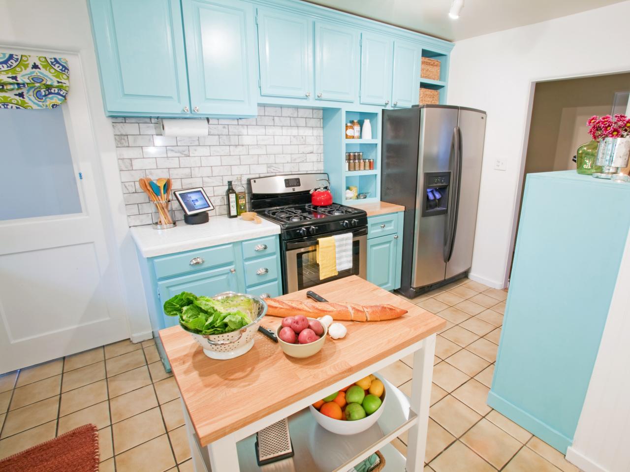 A kitchen with blue cabinets and a wooden cutting board.