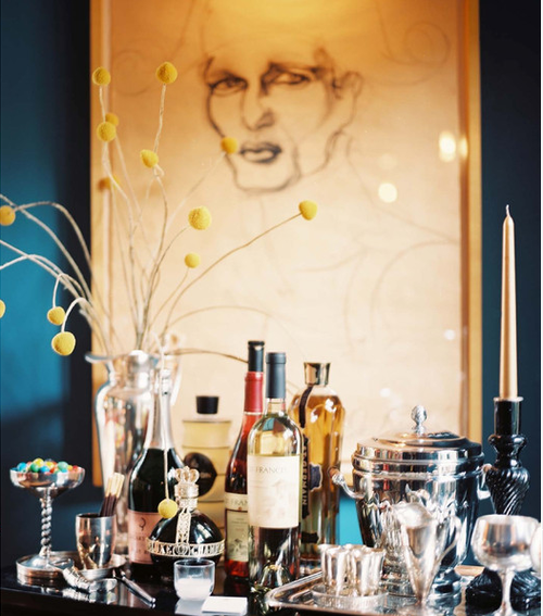 A bar with bottles of wine and a drawing on the wall perfect for home bars.