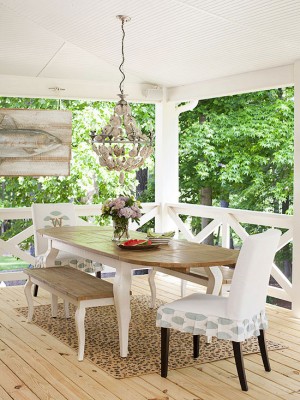 A wooden front porch with a table and chairs.