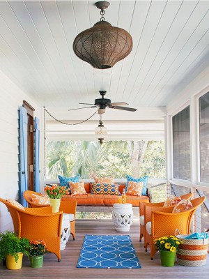 A front porch with orange chairs and a ceiling fan.