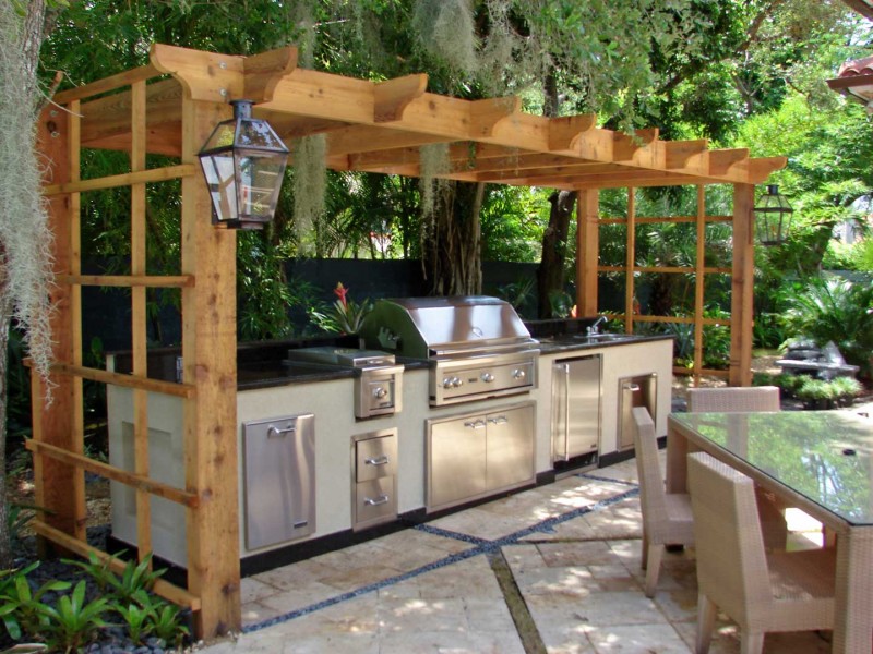 A wooden pergola with an outdoor kitchen.