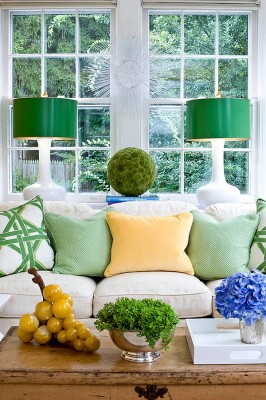 A living room with a white couch and green pillows, perfect for spring.