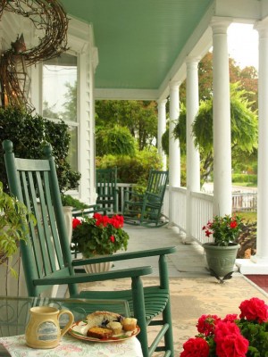 A front porch adorned with rocking chairs and flowers.