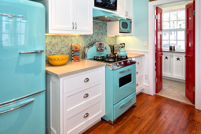 A vintage kitchen with a blue refrigerator and a red stove.