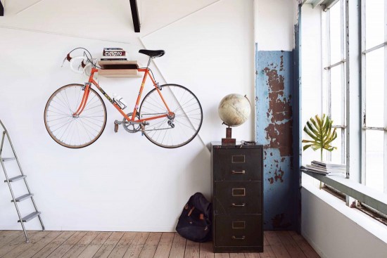A bicycle is hanging on a wall in a bicycle storage room.
