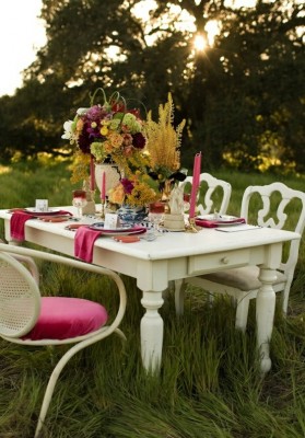 A white table with pink chairs in a backyard.