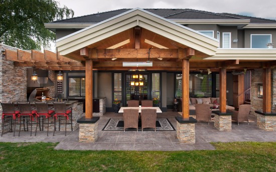 A large backyard with a covered patio featuring an outdoor kitchen.