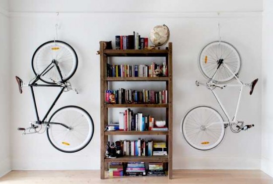 Bicycle storage in a room with hanging bicycles on a bookcase.