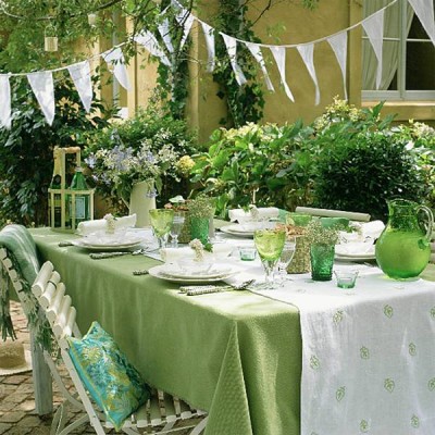A backyard dining table set with green and white tablecloths.