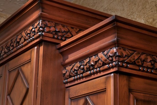 A close up of a traditional wooden cabinet with ornate carvings in a kitchen.