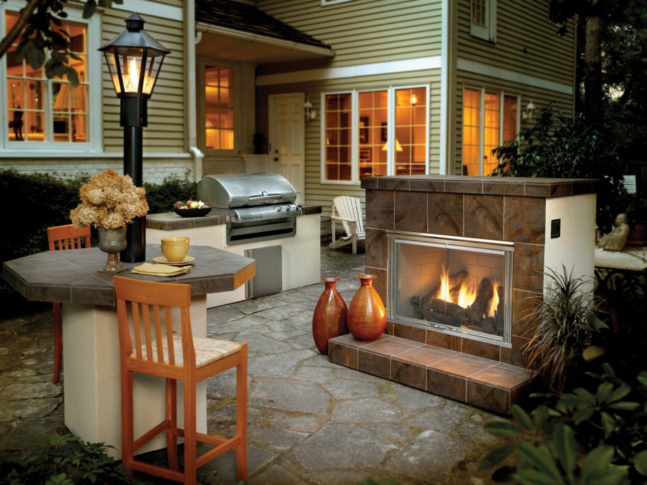 An outdoor kitchen with a fire pit and a grill.