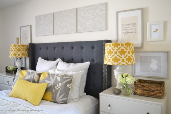 A bedroom with a grey headboard and yellow pillows, perfect for choosing and styling a bedside table.