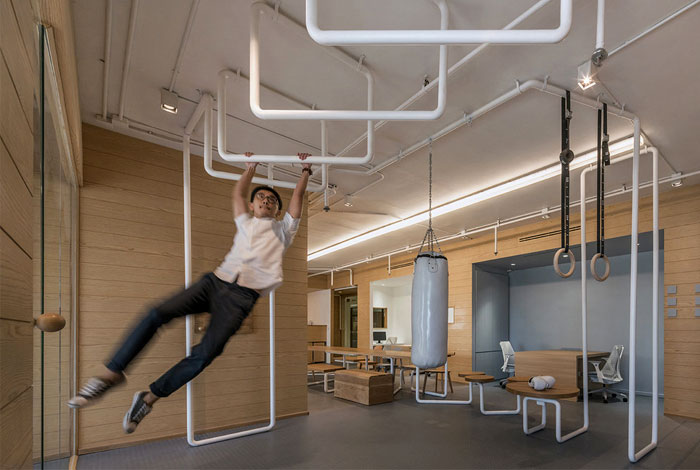 Man swinging on indoor gym pipes in modern office.