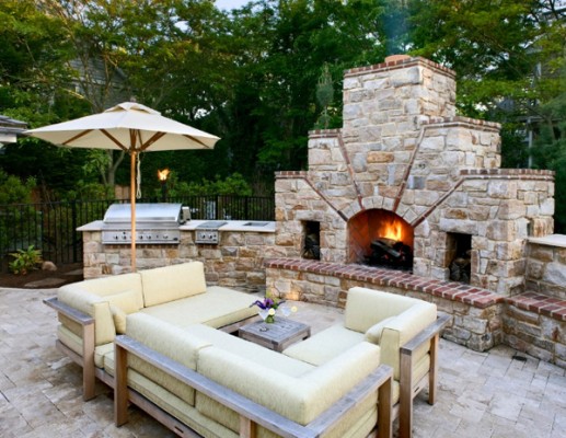 An open outdoor kitchen with comfy seating and fireplace (onekindesign)