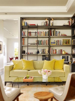 A home library featuring a yellow couch and bookshelves.