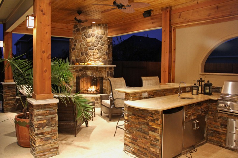 An outdoor kitchen with a fireplace and grill.