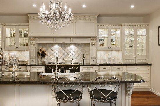 A traditional kitchen with white cabinets and a chandelier.