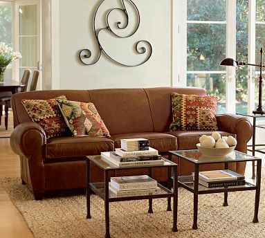 A living room with a brown leather couch and alternative coffee table options.