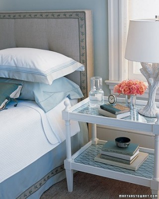 A blue and white bedroom with a bed and a nightstand, choosing and styling a bedside table.